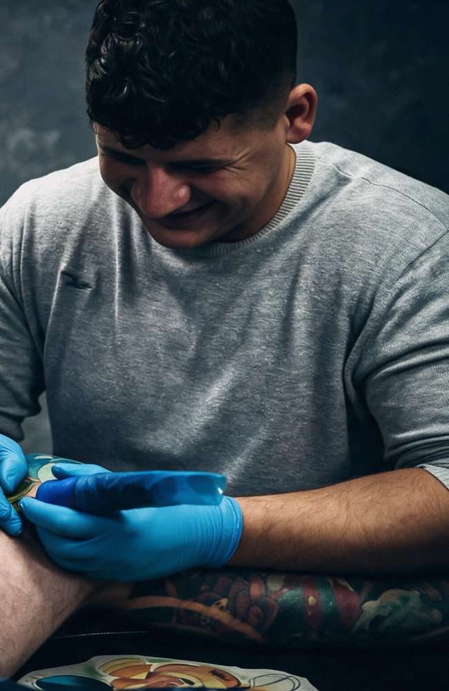 Stan, owner of STATTOOS, tattooing a client in the studio